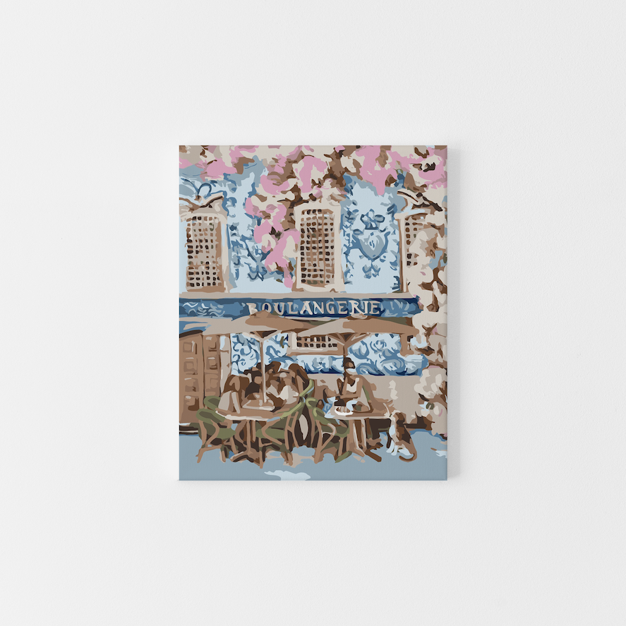 Paint Like Frida’s French Breakfast Big Framed Canvas — a dreamy paint by numbers scene of a blue Parisian boulangerie with pink florals, café chairs, and people enjoying croissants outdoors, framed in a custom floating frame.
